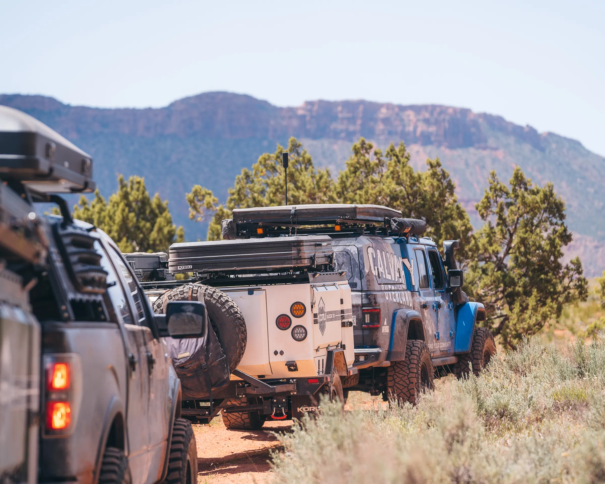 Trucks and trailers staged in the field beneath a mesa